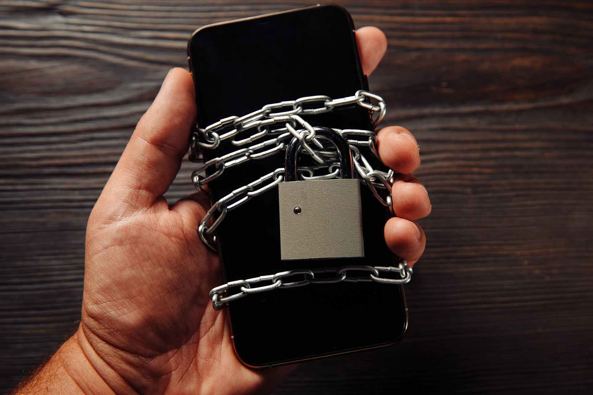 man-s-hand-holding-smartphone-with-padlock-concept-smartphone-protection-against-malware-antivirus